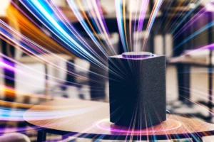 Caixa de som inteligente preta sobre mesa de madeira com efeitos de luz coloridos em movimento