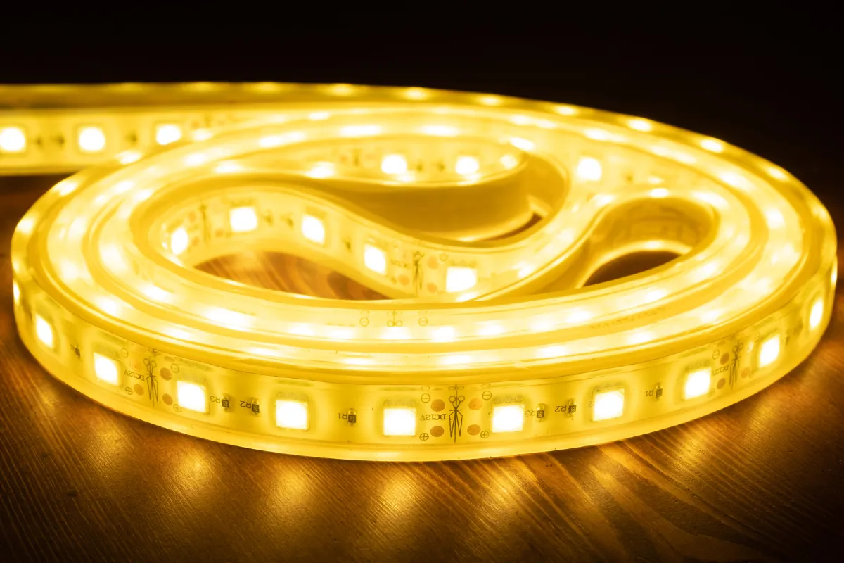 fita de led amarelo enrolada e acesa sobre uma superficie de madeira