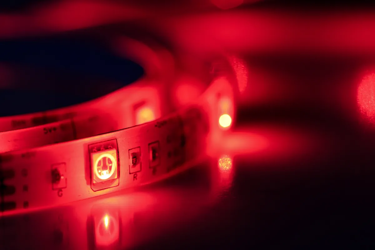 Fita de LED emitindo luz vermelha sobre uma superfície escura com pequenos pontos de iluminação acesos.