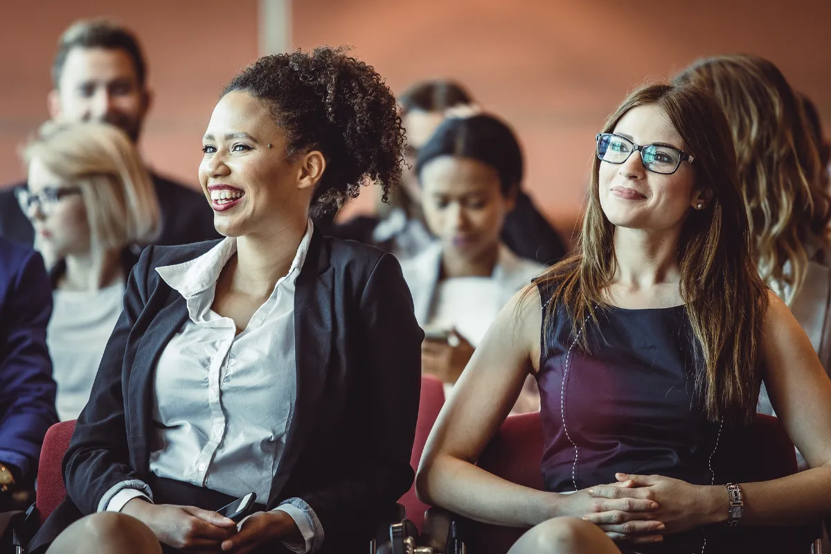 Participantes sentados assistindo a uma apresentação durante uma conferência corporativa em ambiente profissional.